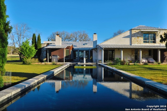 Limestone ranch-style starter home with a live oak in the front yard on a quiet Hill Country street near Boerne, Texas